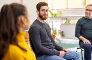 This image shows a man feeling at ease during a group therapy session